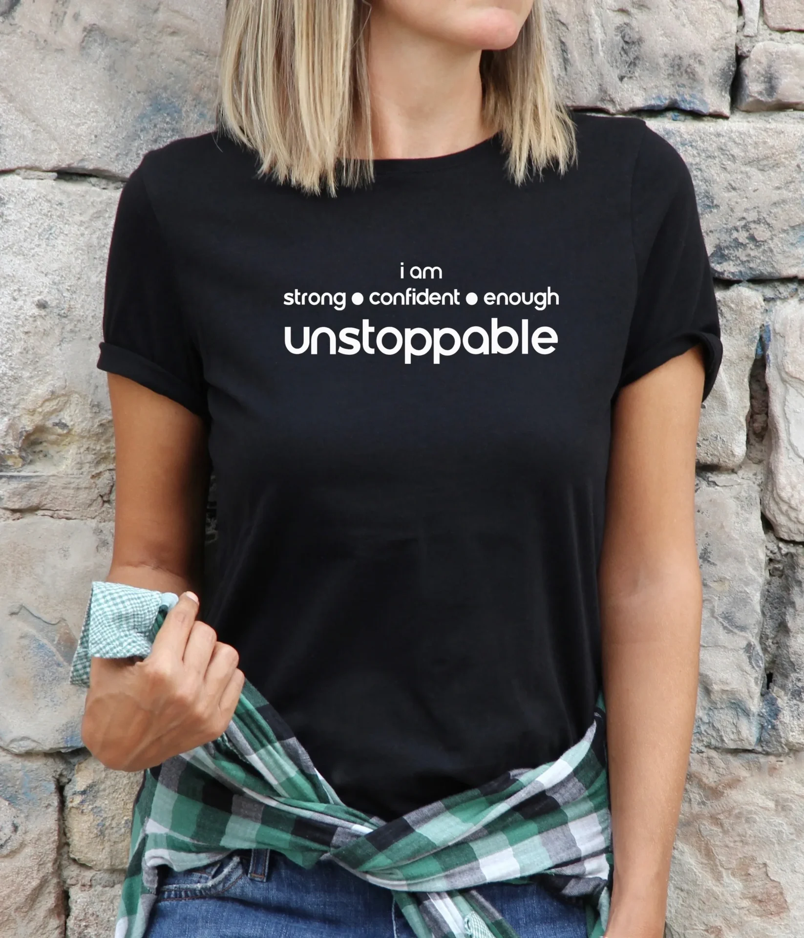 A woman wearing a black shirt with the words unstoppable on it.