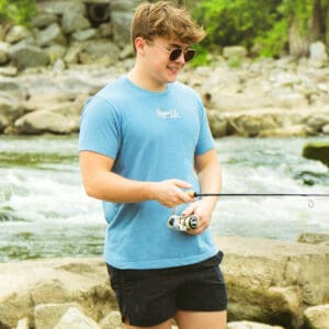 A man standing on rocks holding a fishing rod.