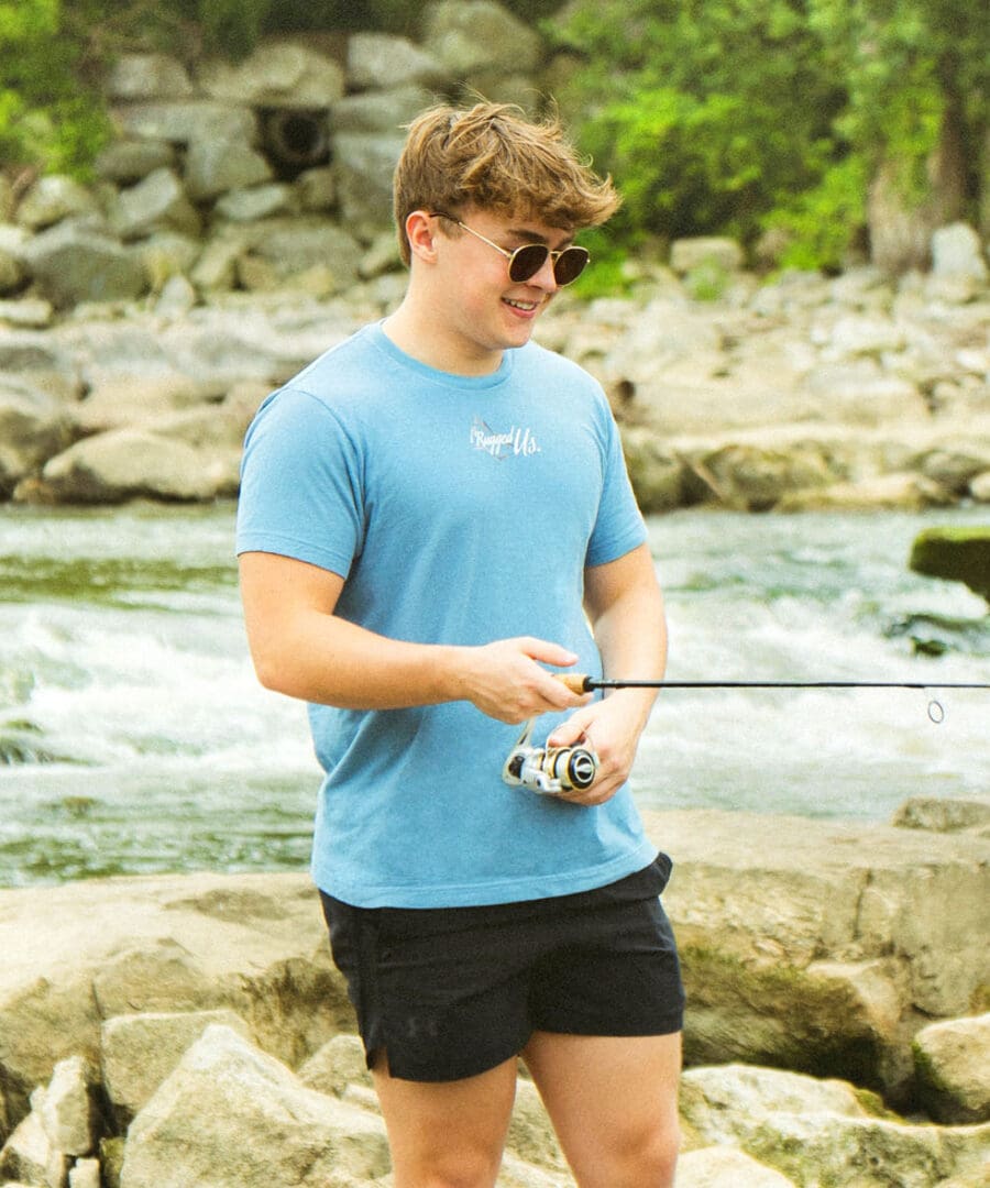 A man standing on rocks holding a fishing rod.