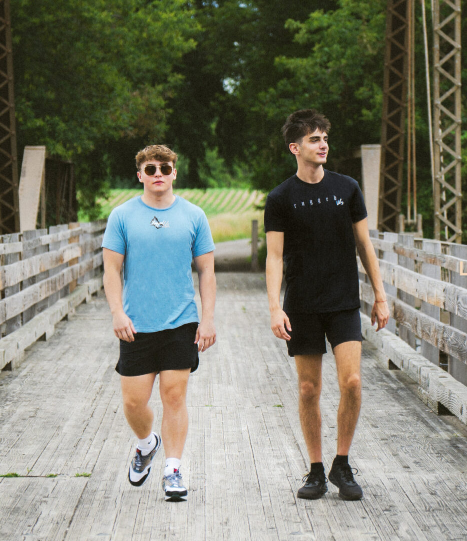 Two young men walking across a bridge.