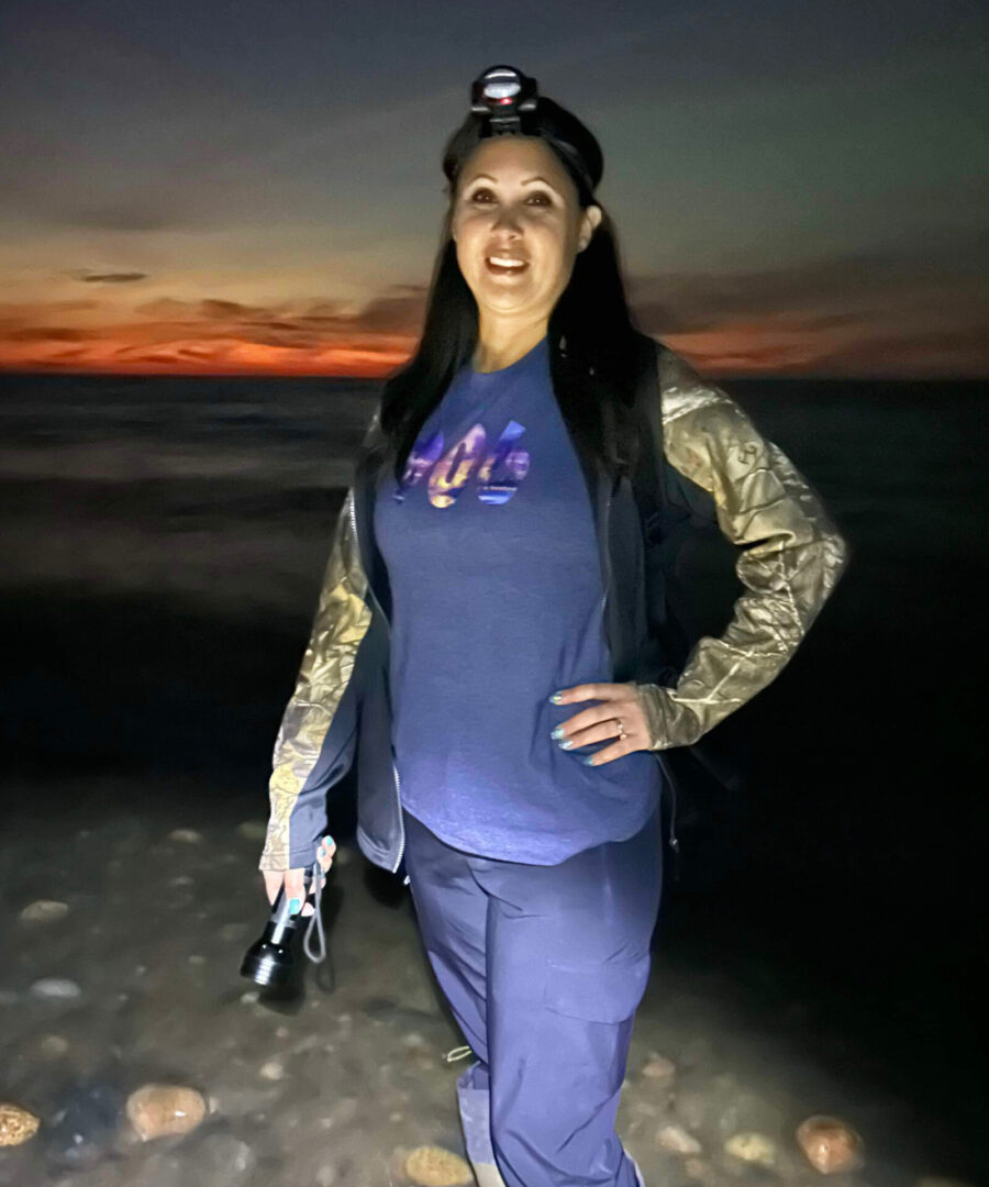 A woman standing on the beach holding a camera.